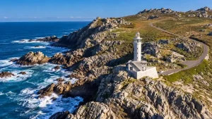 Faro de Punta Nariga rodeado de acantilados rocosos y el océano Atlántico, en la Ruta Oriental por Costa da Morte.