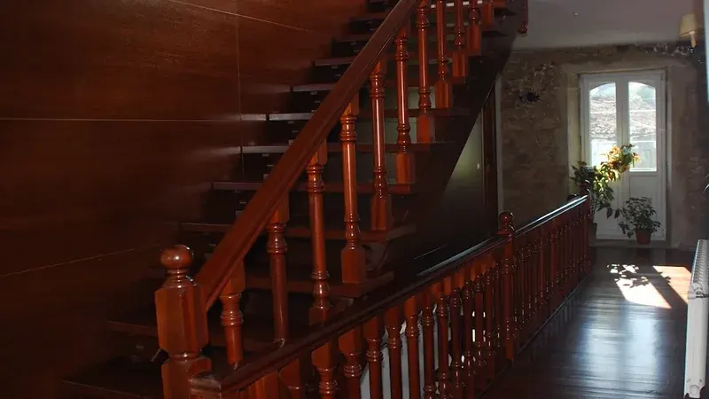 Escalera interior de madera de Casa do Vento, con barandilla tradicional, suelo de madera y paredes de piedra.